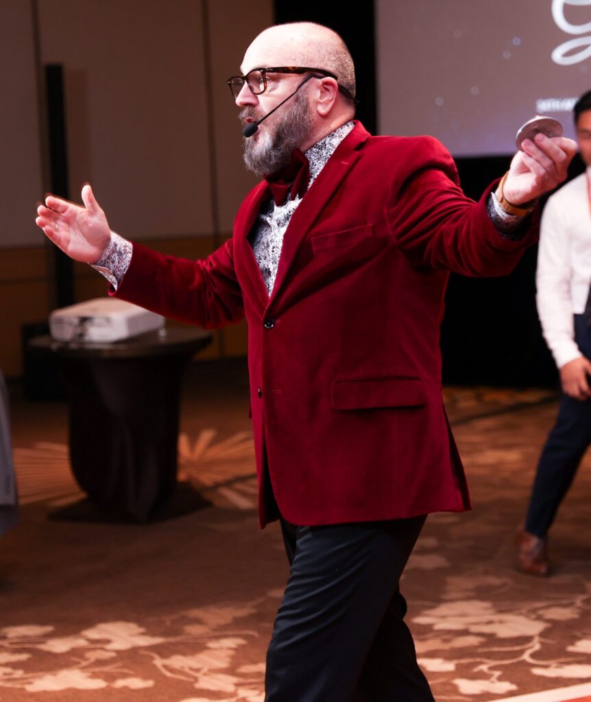 Auctioneer gestures passionately holding paddle while engaging gala audience.