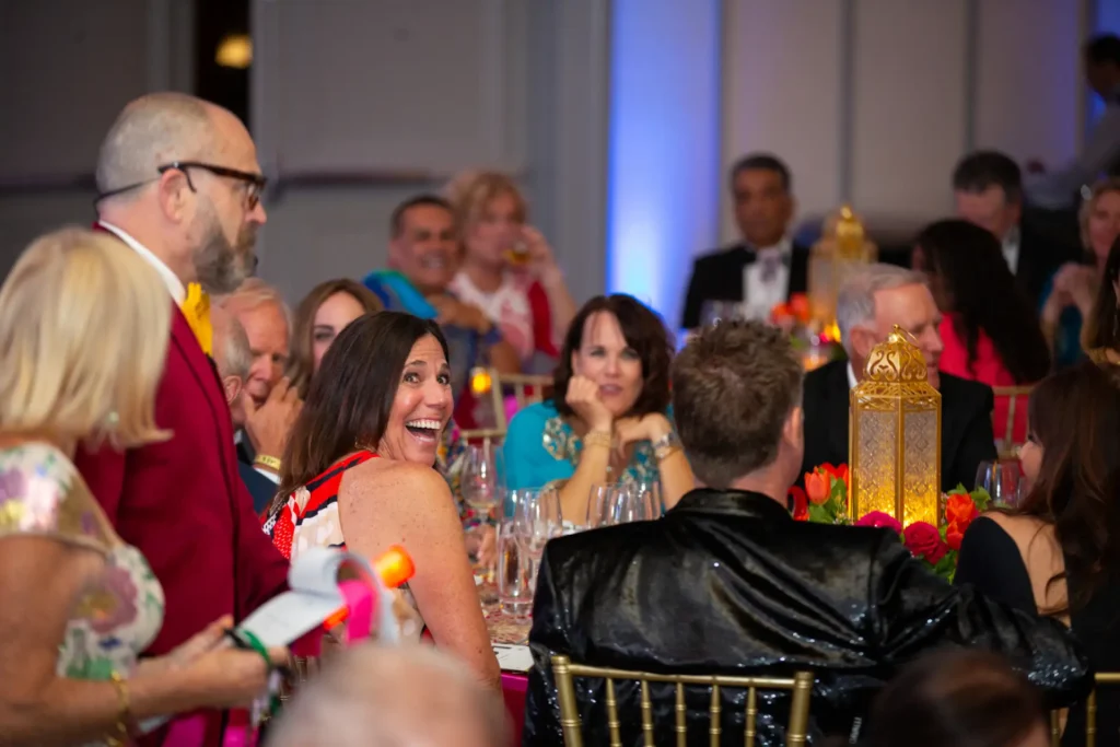 Smiling woman looks at host as he interacts with guests.